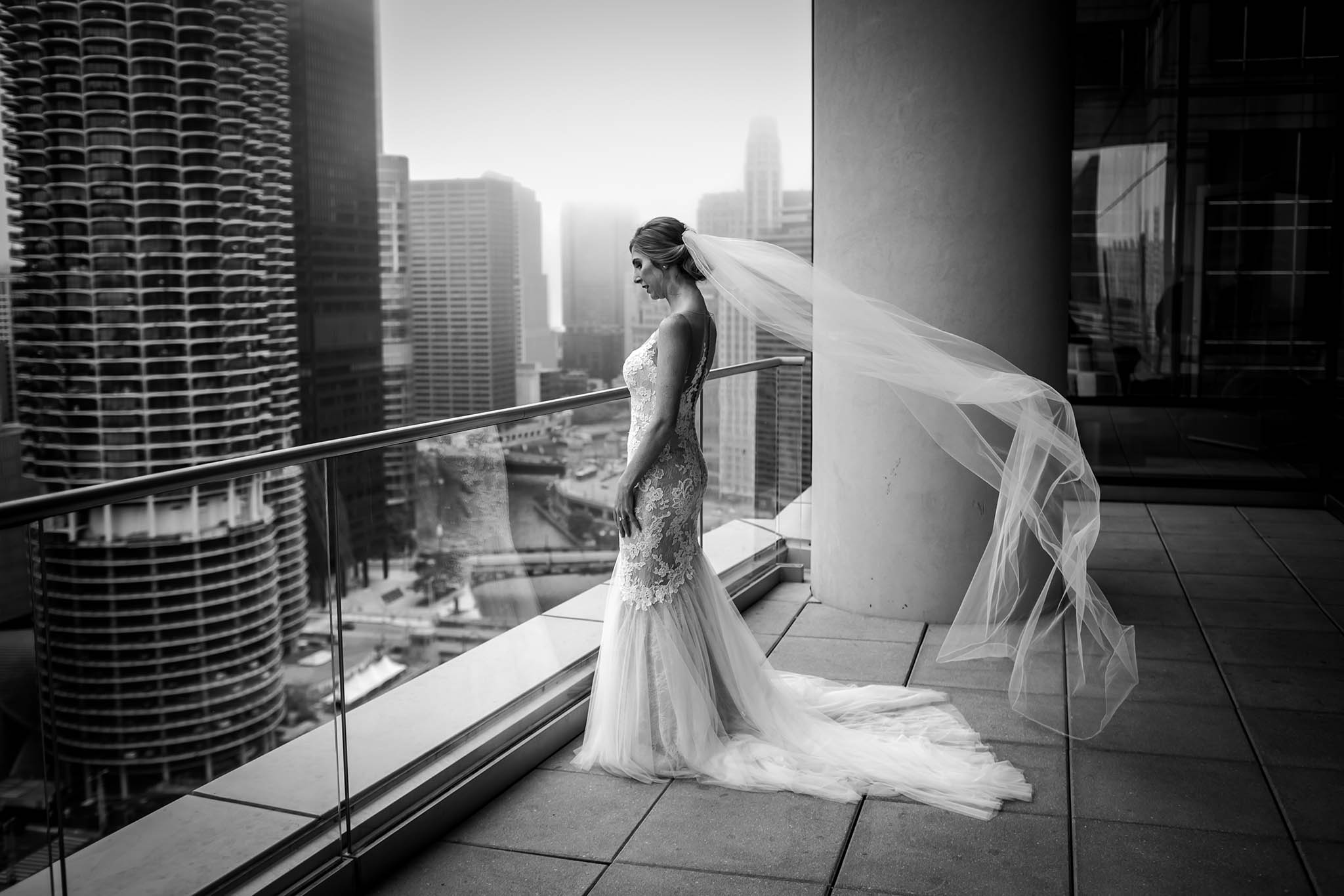 Bride looking over the balcony from a high-rise event venue in Chicago - by WS Photography